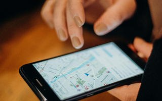 Person, der bruger en smartphone til at finde virksomhedens placering på Google Maps, som en del af optimering via Google My Business.